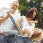 Happy family enjoying playful moments outside on a sunny day.